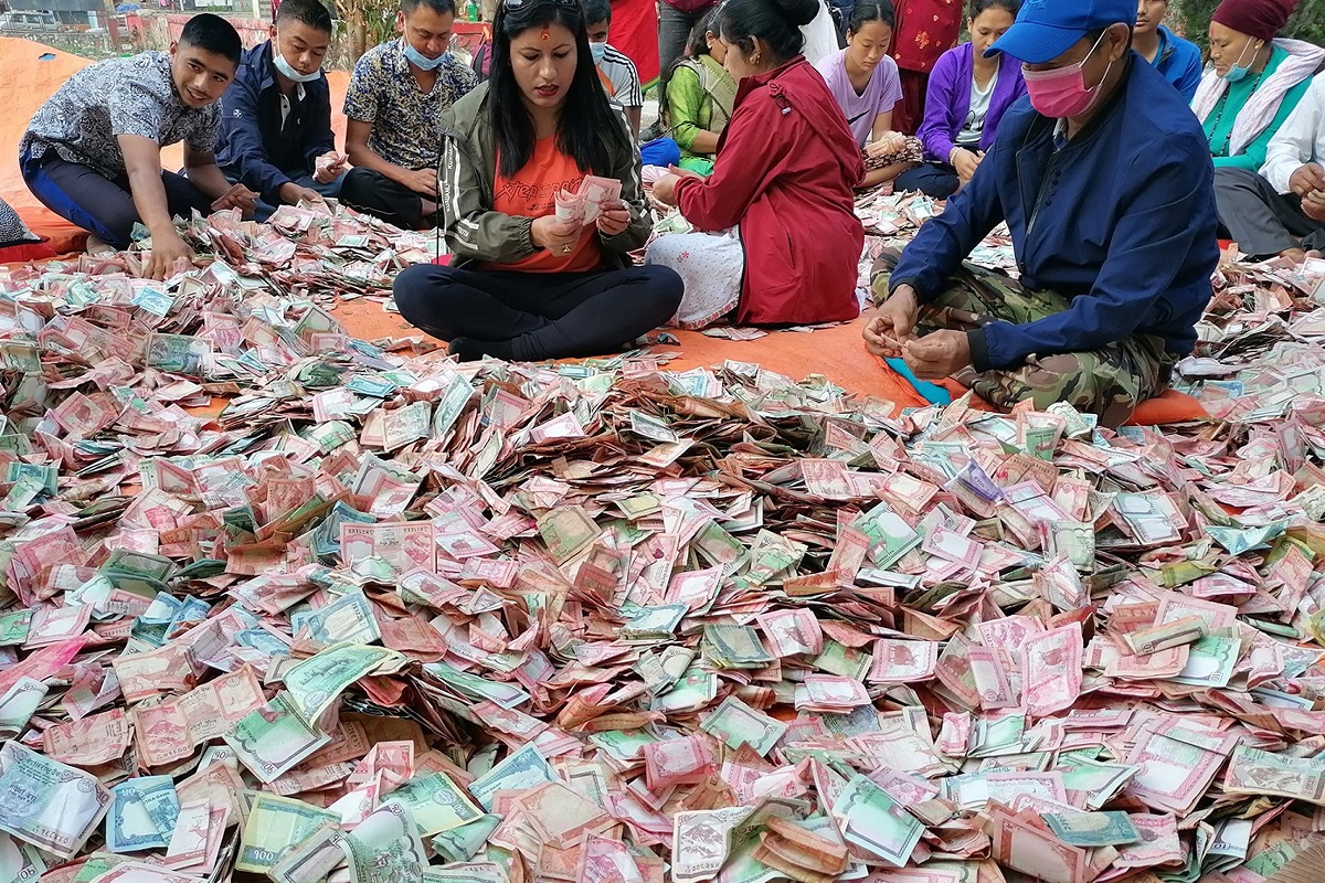 Office-bearer counting offerings made by devotees at Galeshwor temple